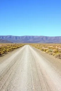 A gravel road running straight towards distant Karoo mountains
